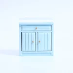 Sky blue miniature kitchen cabinet with white top, featuring a horizontal drawer and double doors with vertical grooved panels, perfect for coastal dollhouse themes.