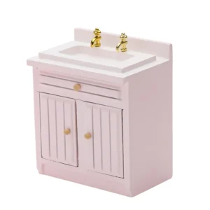 Miniature bathroom vanity in soft pink featuring an integrated sink, gold-tone dual faucets, one drawer, and double doors with vertical panels, perfect for dollhouse bathrooms.