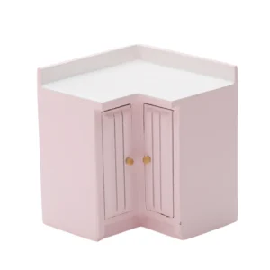 Miniature L-shaped corner cabinet in soft pink featuring double doors with vertical grooves and brass knobs, perfect for dollhouse kitchen corner storage.