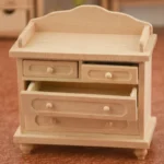 Unfinished classic miniature wooden chest of drawers featuring four functional drawers and a decorative backrest, designed for dollhouse use.