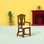 Miniature brown wooden chair featuring a decorative backrest and white cushion, perfect for dollhouses.