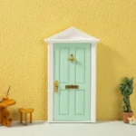 Miniature mint green door featuring elegant gold accents, designed for dollhouse decoration.