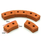 Set of 100 miniature curved terracotta bricks measuring 3cm x 1.3cm x 0.9cm, featuring dual mounting holes and curved design for creating arches and curved walls, in authentic clay orange color with smooth finish