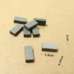 Set of 100 miniature rectangular gray clay blocks, featuring a smooth matte finish and uniform dimensions of 1.6cm x 0.8cm x 0.45cm, perfect for 1:16 scale architectural models